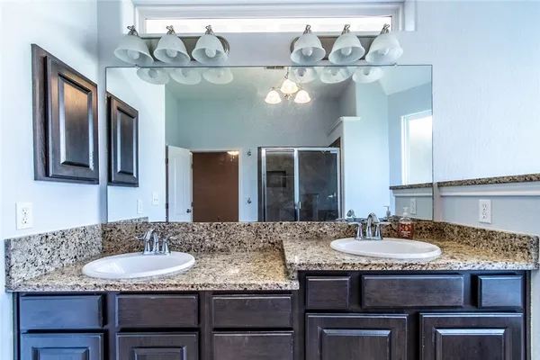 a spacious bathroom with a granite countertop double vanity sink a large mirror and a bathtub