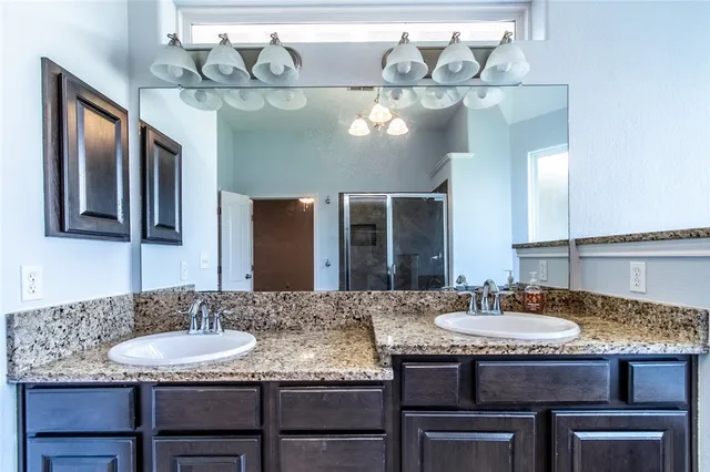 a spacious bathroom with a granite countertop double vanity sink a large mirror and a bathtub
