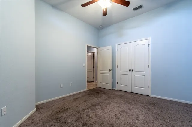 an empty room with a chandelier fan and windows