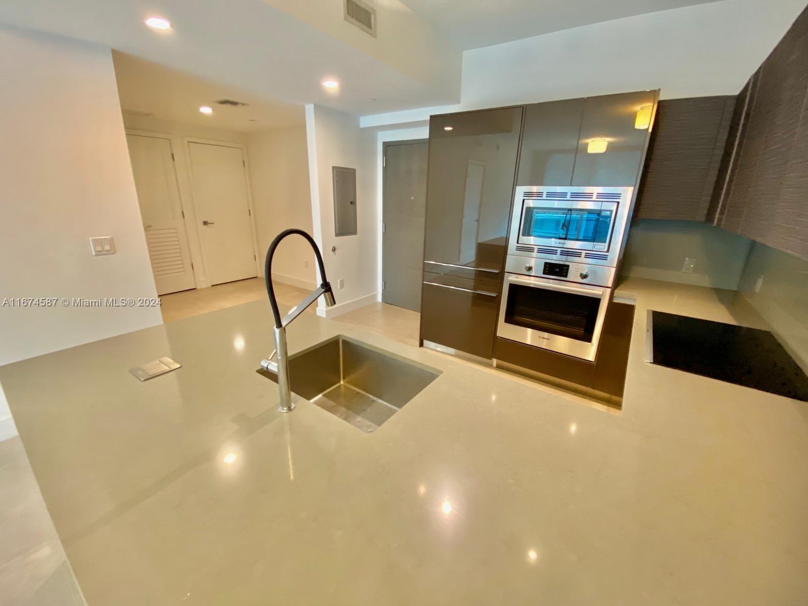 1080 Brickell Avenue, Unit 3107 Miami, FL 33131 - Photo 5 of 19 a kitchen with kitchen island a sink stainless steel appliances and cabinets