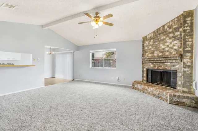 an empty room with windows and fireplace