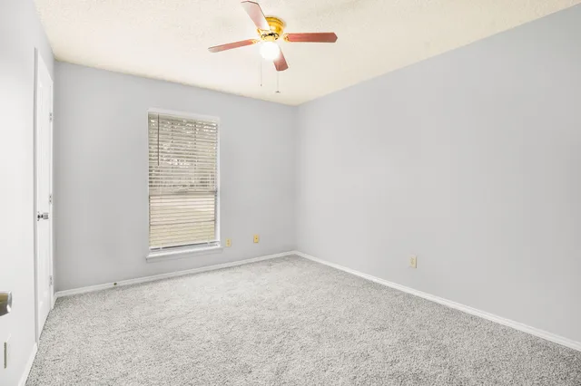 an empty room with windows and fan