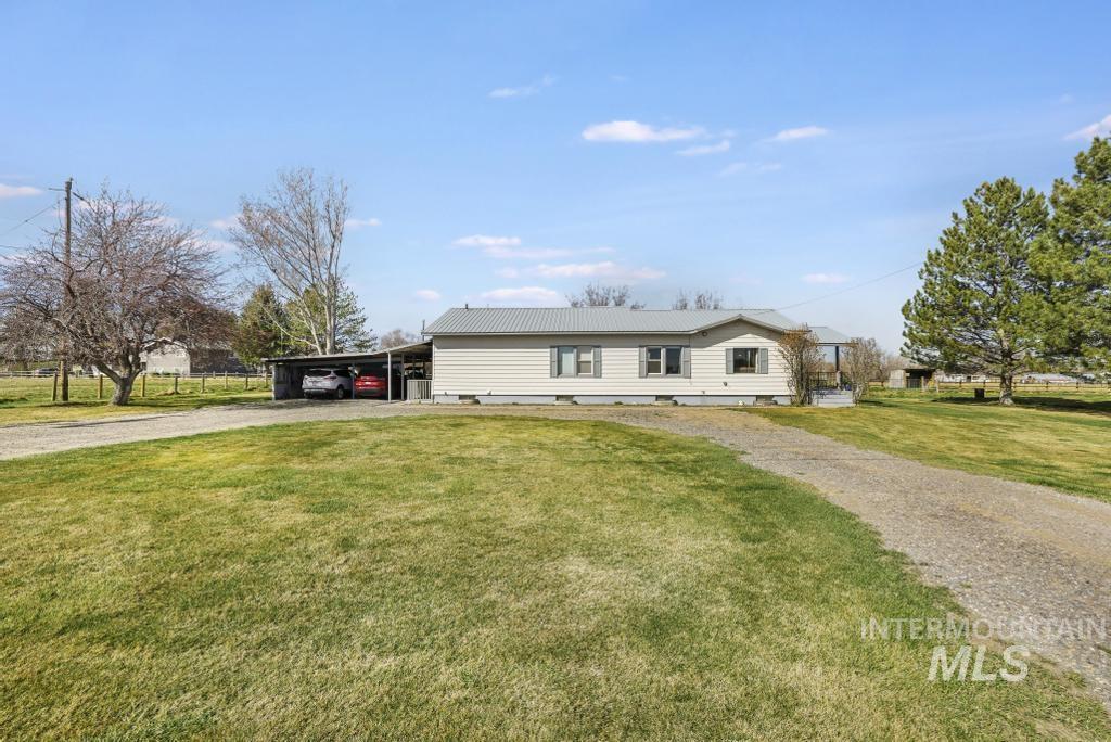 3985 North 2300 E Road Filer, ID 83328 - Photo 1 of 35 View of front of property featuring gravel driveway, a front lawn, a carport, and a metal roof
