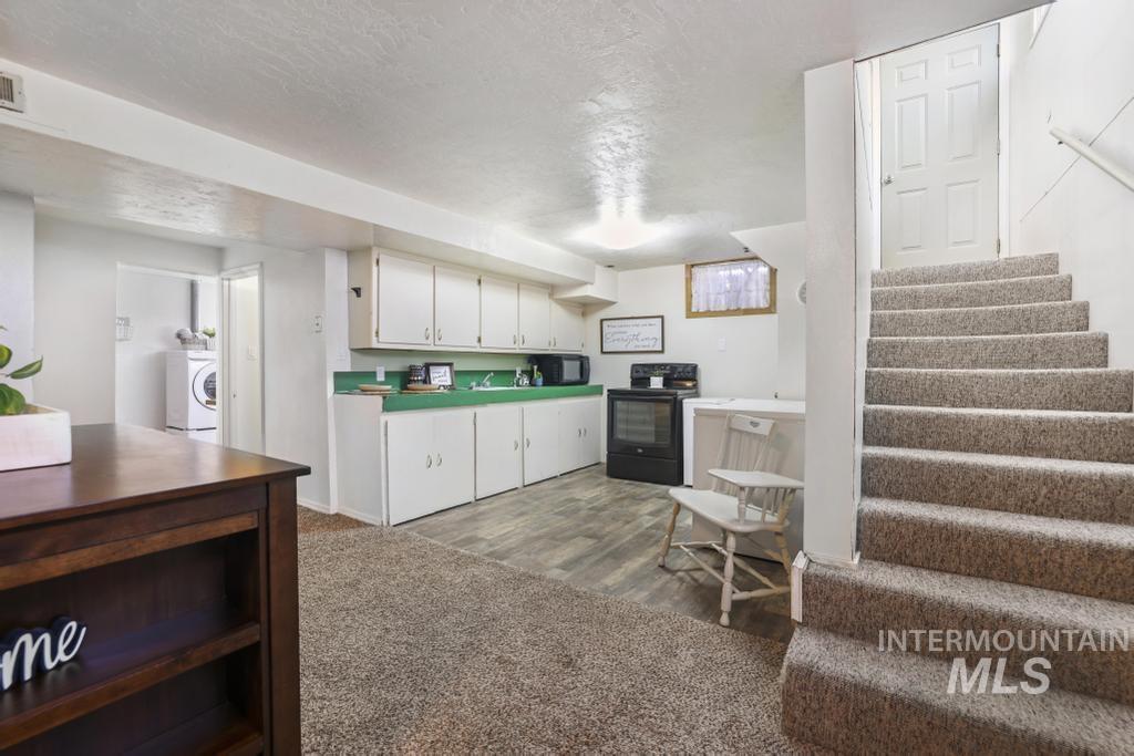 3985 North 2300 E Road Filer, ID 83328 - Photo 20 of 35 Kitchen featuring black appliances, white cabinetry, a textured ceiling, washer / dryer, and dark carpet