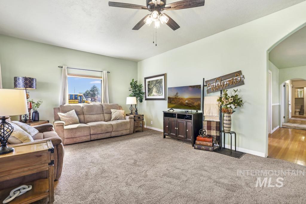 3985 North 2300 E Road Filer, ID 83328 - Photo 4 of 35 Living room featuring arched walkways, a ceiling fan, and light colored carpet