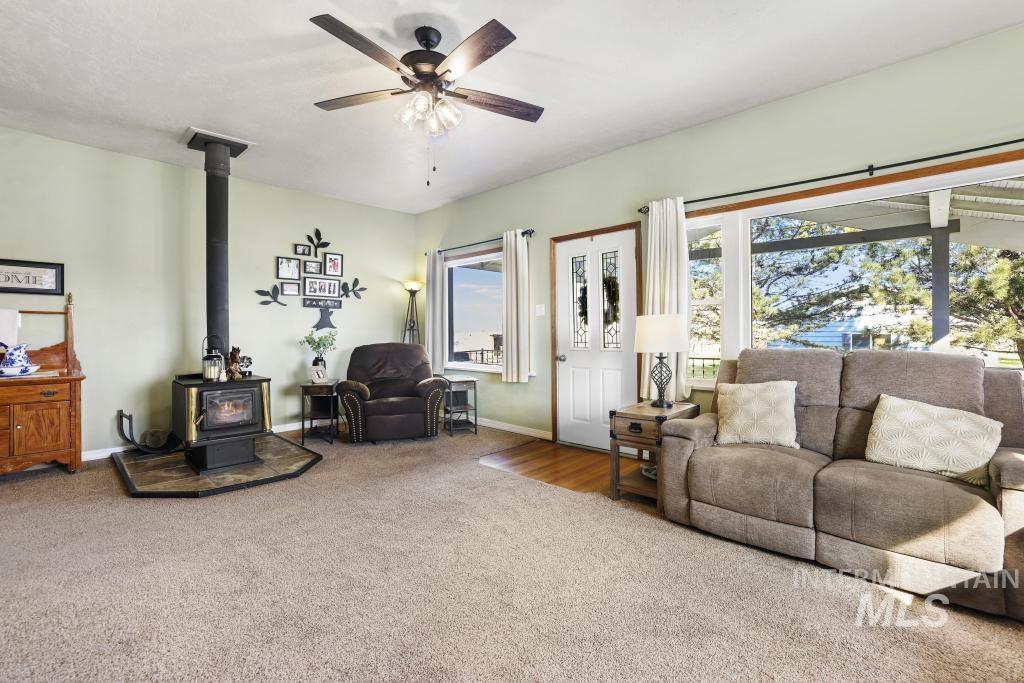 3985 North 2300 E Road Filer, ID 83328 - Photo 5 of 35 Carpeted living room featuring a wood stove and a ceiling fan