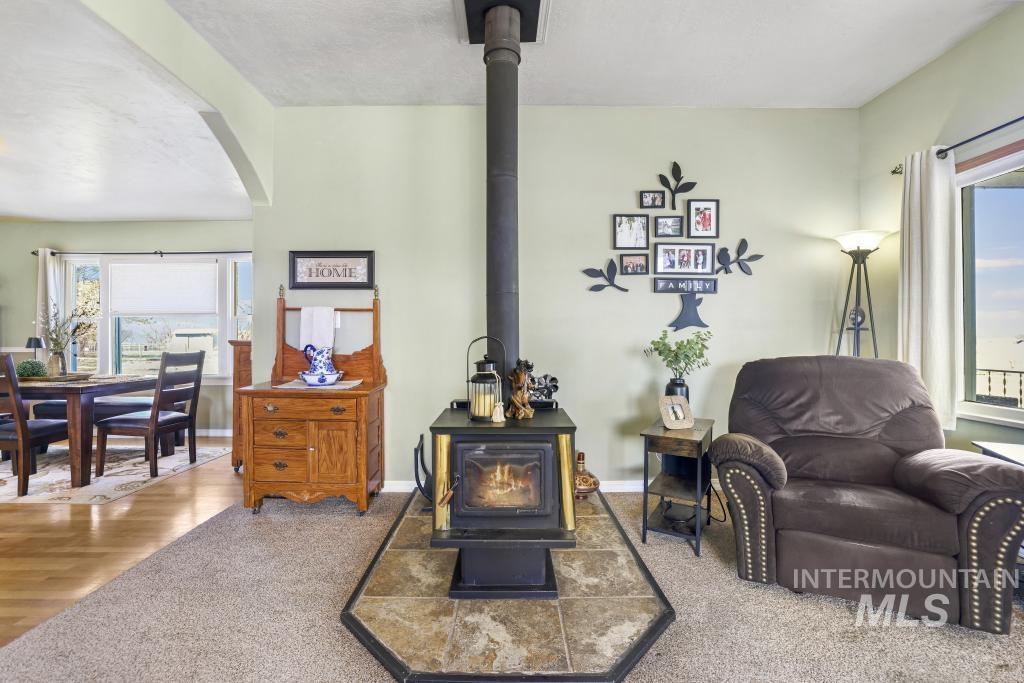 3985 North 2300 E Road Filer, ID 83328 - Photo 6 of 35 Sitting room featuring arched walkways, a wood stove, and wood finished floors