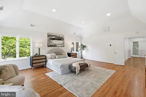 a view of a hallway with wooden floor and a bathroom