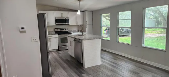 a kitchen with stainless steel appliances granite countertop a stove top oven a sink and a refrigerator