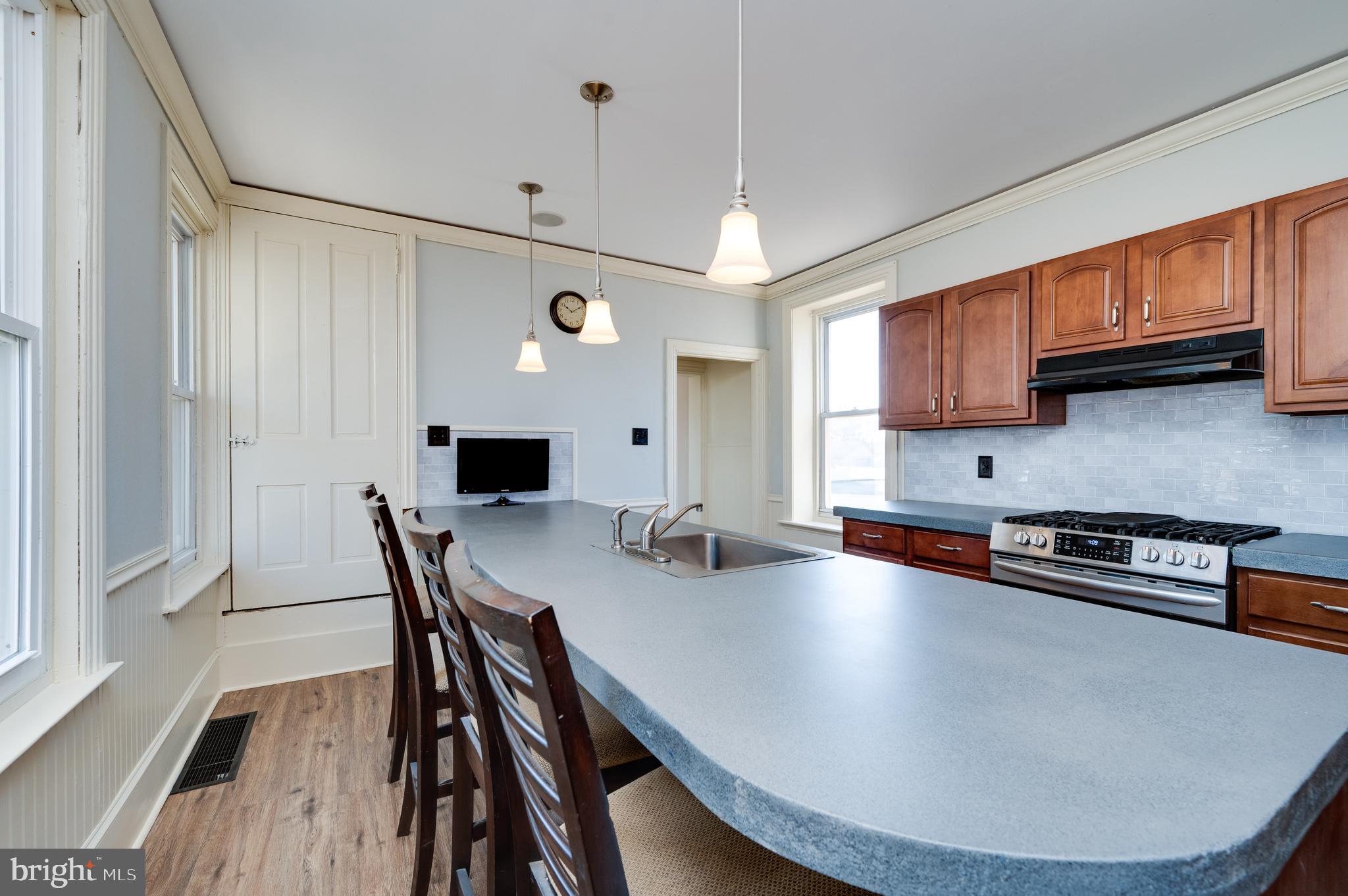 800 Mount Laurel Road Temple, PA 19560 - Photo 19 of 42 a kitchen with stainless steel appliances granite countertop a stove a refrigerator a sink a dining table and chairs with wooden floor
