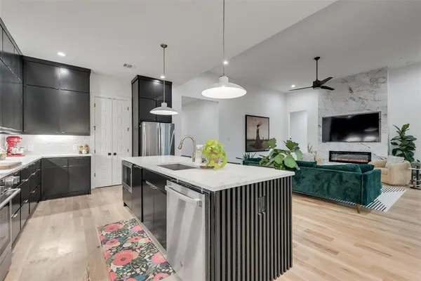 a kitchen with stainless steel appliances kitchen island granite countertop a sink dishwasher a dining table and chairs with wooden floor