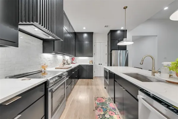a kitchen with stainless steel appliances a sink a stove and a wooden floors