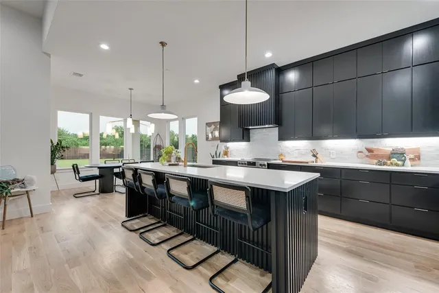 a kitchen with stainless steel appliances granite countertop a sink a stove and a wooden floors
