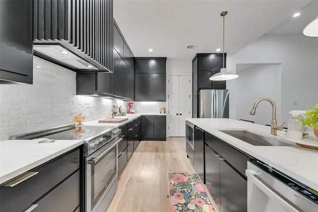a kitchen with stainless steel appliances a sink a stove and a wooden floors