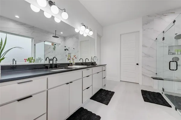 a spacious bathroom with double vanity a mirror and a shower