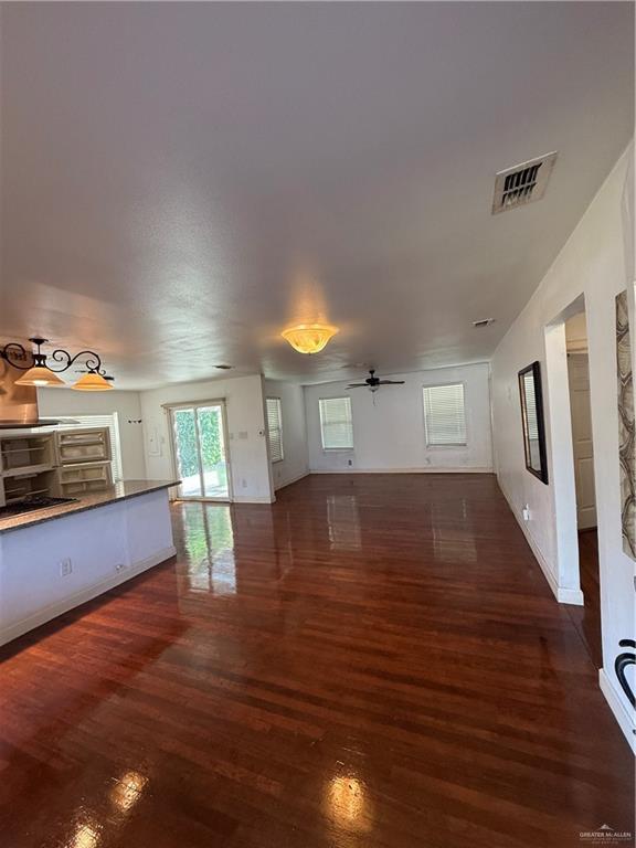 708 North 6th Street McAllen, TX 78501 - Photo 3 of 27 Unfurnished living room featuring dark wood-style flooring and a ceiling fan