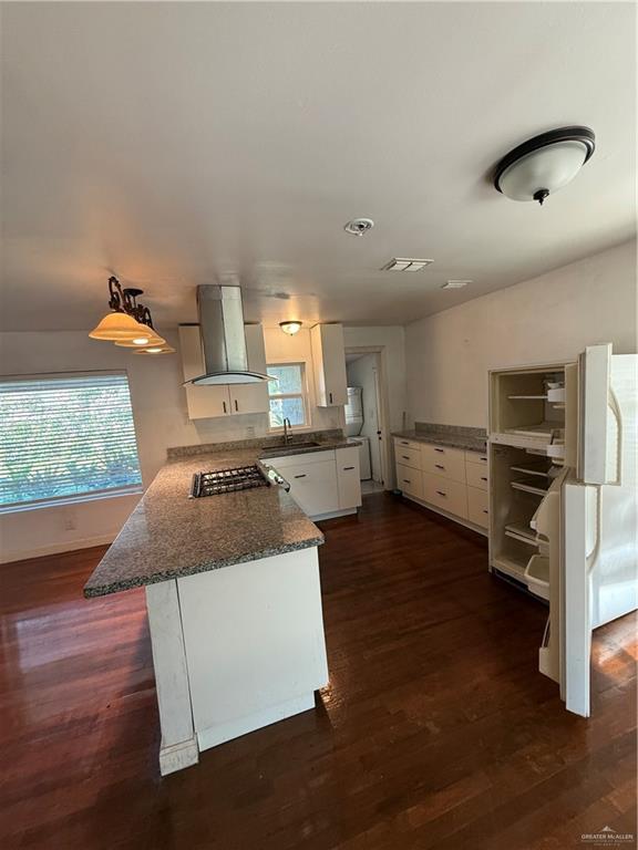 708 North 6th Street McAllen, TX 78501 - Photo 4 of 27 Kitchen featuring white cabinets, a peninsula, exhaust hood, dark wood-type flooring, and dark stone countertops