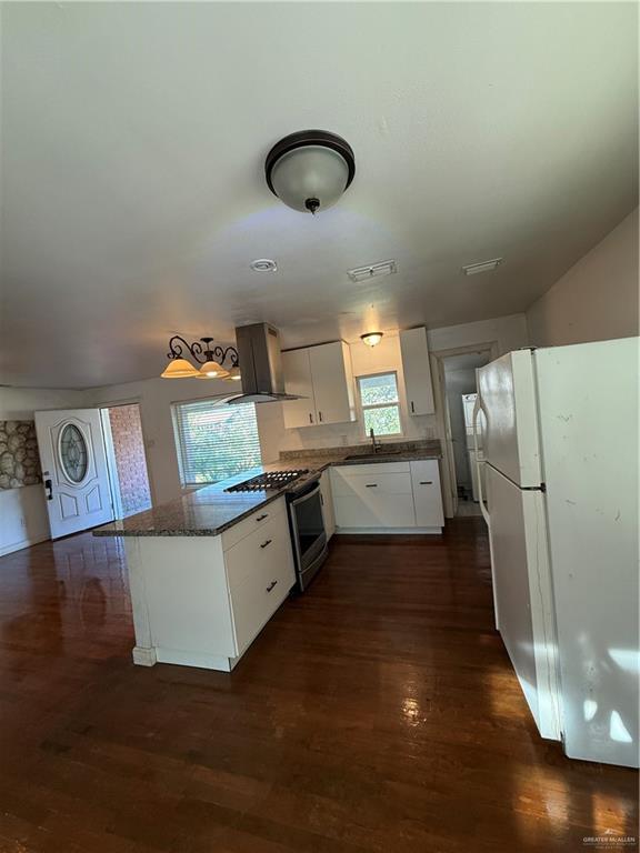 708 North 6th Street McAllen, TX 78501 - Photo 5 of 27 Kitchen with white cabinetry, refrigerator, wall chimney exhaust hood, stainless steel stove, and a peninsula