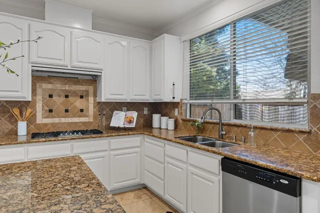 a kitchen with granite countertop a sink a stove and cabinets