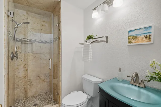 a bathroom with a granite countertop sink a toilet and shower
