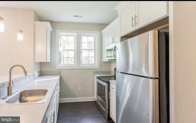 a kitchen with a refrigerator sink and cabinets