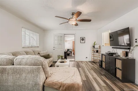a living room with furniture a ceiling fan and a flat screen tv