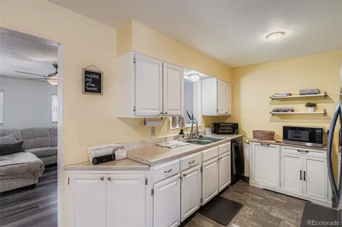 a kitchen with a sink dishwasher stove and white cabinets
