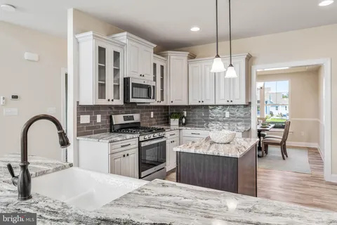 a kitchen with granite countertop a stove and a white cabinets