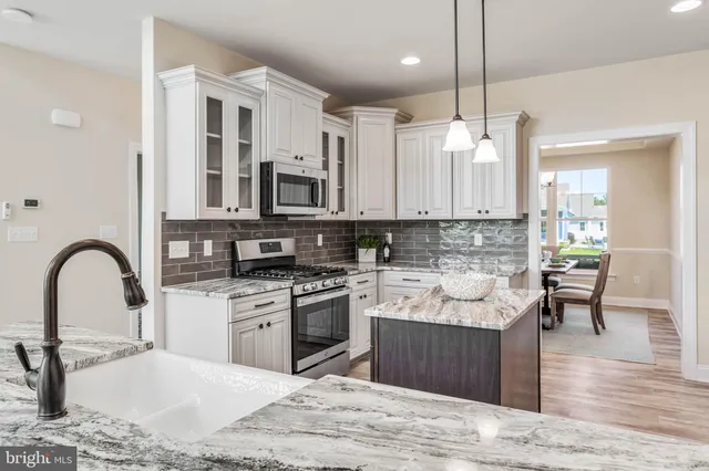 a kitchen with granite countertop a stove and a white cabinets
