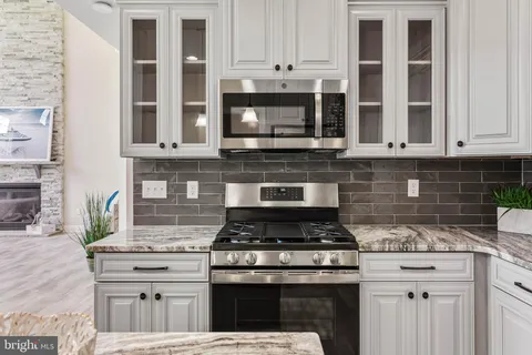 a kitchen with stainless steel appliances granite countertop a refrigerator a sink a stove and oven