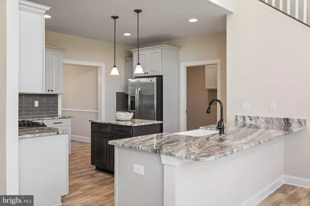 a kitchen with stainless steel appliances granite countertop a stove a sink dishwasher a microwave oven with white cabinets and wooden floor