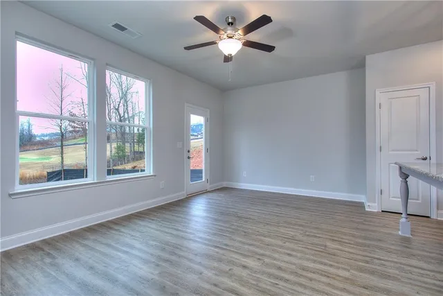 a view of an empty room with a window and wooden floor