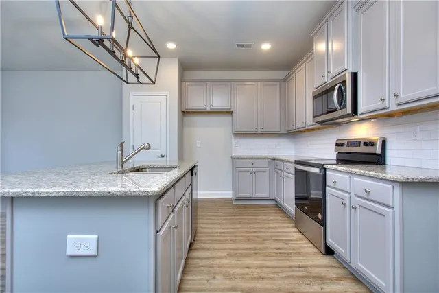 a kitchen with stainless steel appliances granite countertop a sink a stove and cabinets