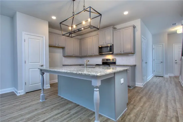 a kitchen with kitchen island granite countertop a sink cabinets and wooden floor