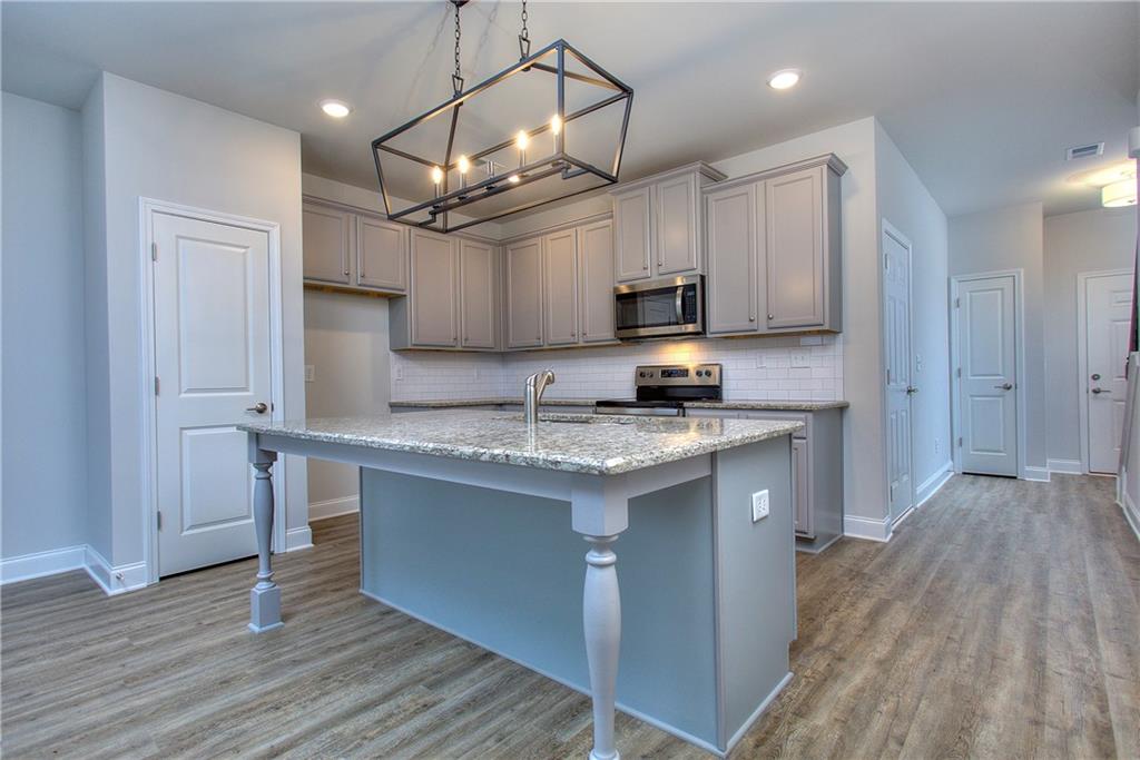 115 Greenview Court Homer, GA 30547 - Photo 6 of 32 a kitchen with kitchen island granite countertop a sink cabinets and wooden floor