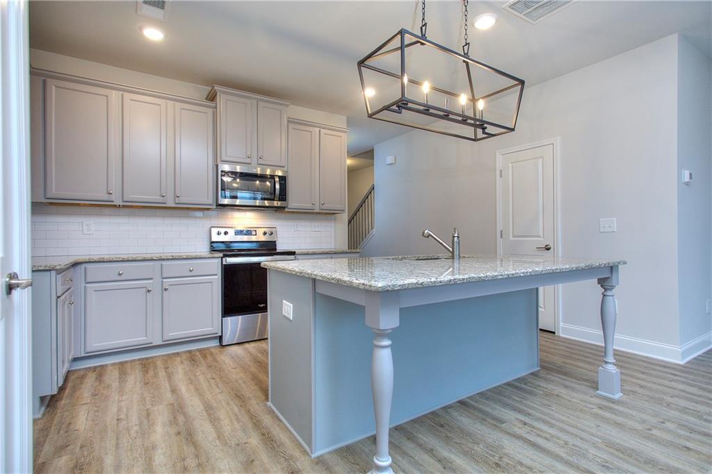 115 Greenview Court Homer, GA 30547 - Photo 8 of 32 a kitchen with kitchen island granite countertop a sink cabinets and wooden floor