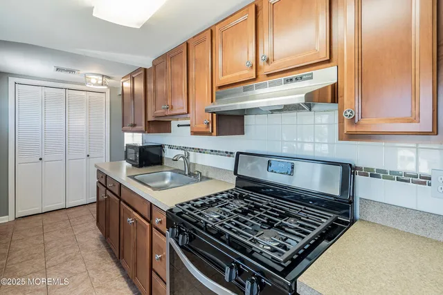 a kitchen with granite countertop a stove sink and cabinets