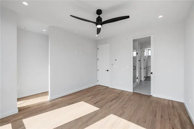 a view of empty room with wooden floor and fan