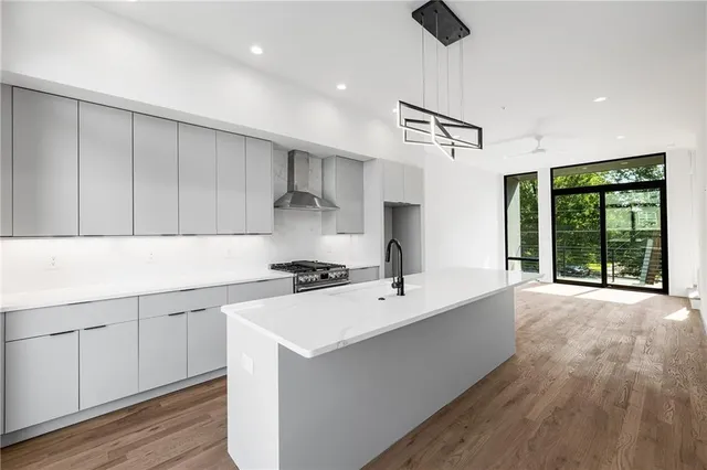 a kitchen with stainless steel appliances a sink stove and wooden floor