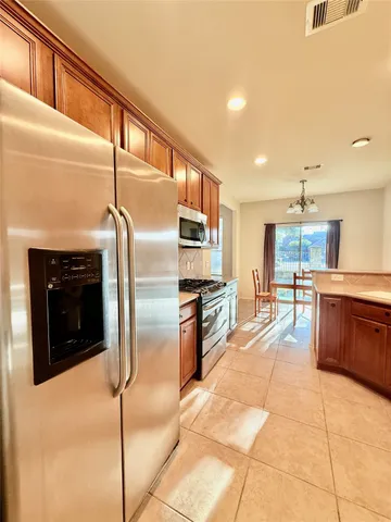 a kitchen with stainless steel appliances kitchen island granite countertop a stove a sink and a refrigerator
