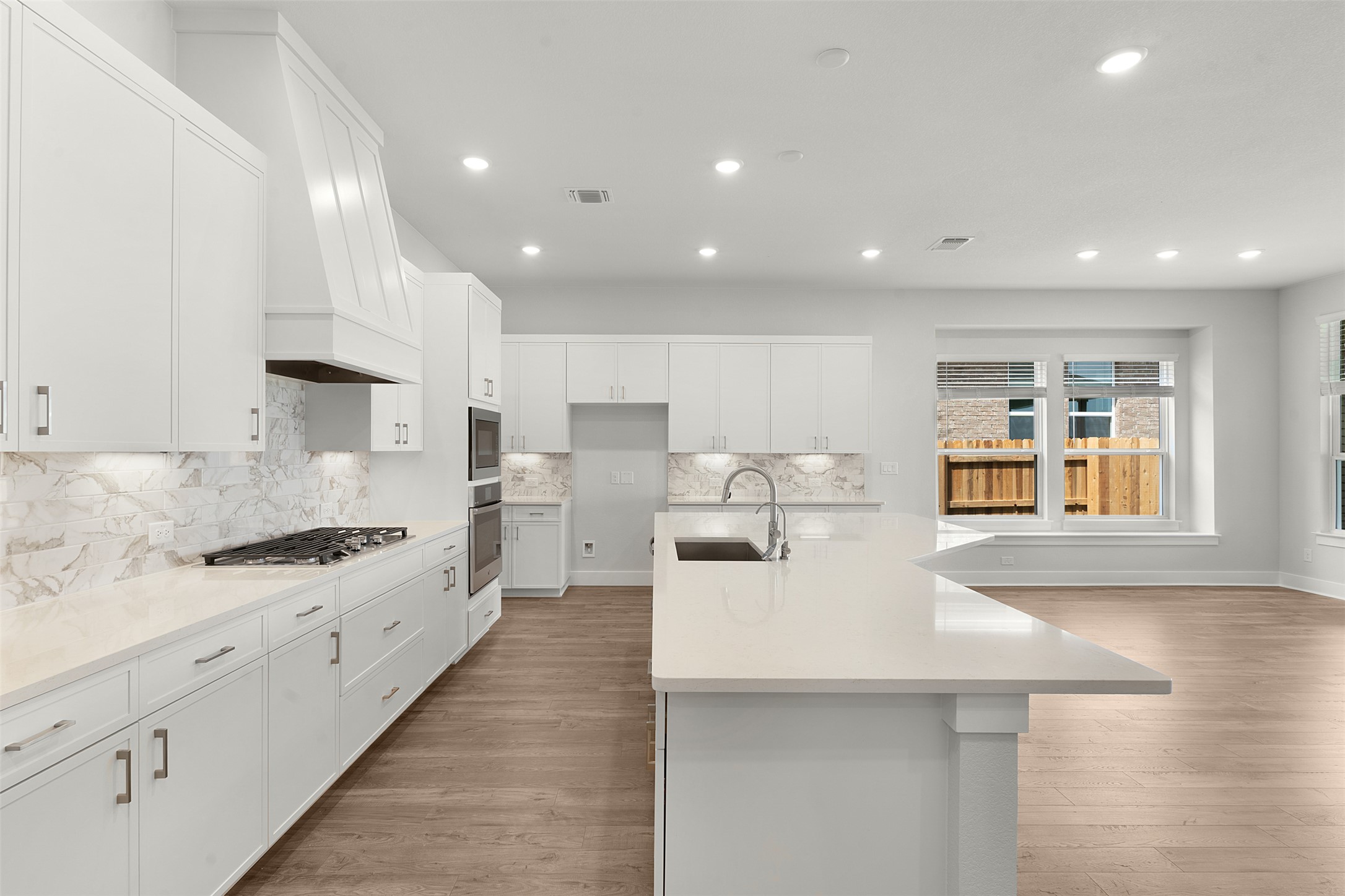1129 Pansy Trail Georgetown, TX 78628 - Photo 11 of 29 Kitchen featuring white cabinetry, light countertops, a gas range with a decorative vent hood, a built-in double oven, and a large central island with an undermount sink