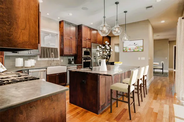 a kitchen with stainless steel appliances kitchen island granite countertop a table chairs and a refrigerator