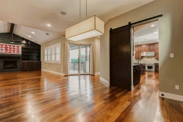 an empty room with wooden floor fireplace and windows