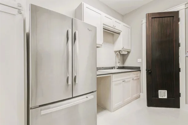 a kitchen with a refrigerator and white cabinets