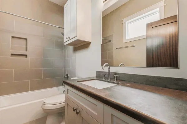 a bathroom with a granite countertop sink a toilet a mirror and bathtub