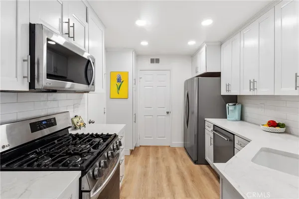a kitchen with stainless steel appliances kitchen island granite countertop a stove and a refrigerator