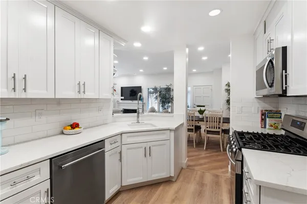 a kitchen with stainless steel appliances a sink a stove a refrigerator cabinets and living room view