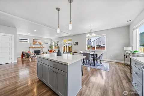 a kitchen with stainless steel appliances granite countertop a refrigerator a sink dishwasher a dining table and chairs with wooden floor