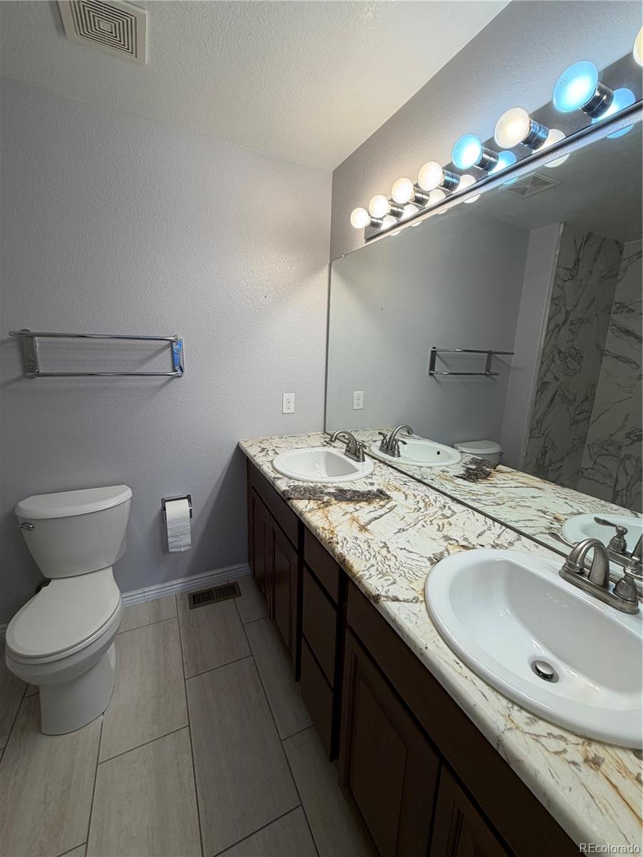 6369 Cole Lane Arvada, CO 80004 - Photo 5 of 21 a bathroom with a granite countertop sink a toilet and a mirror
