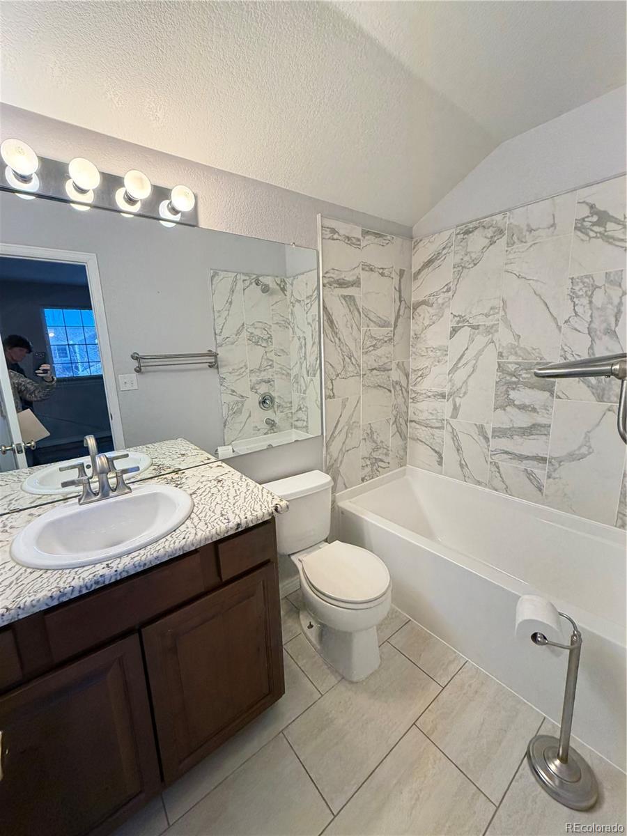 6369 Cole Lane Arvada, CO 80004 - Photo 10 of 21 a bathroom with a granite countertop sink a toilet a mirror a bathtub and shower